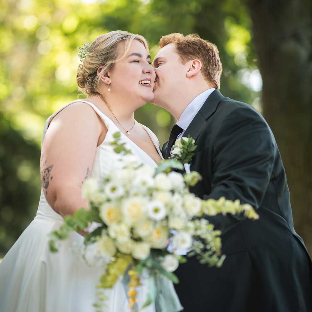 Braut und Bräutigam küssen sich hinter einem Braut und Bräutigam küssen sich hinter dem Brautstrauß