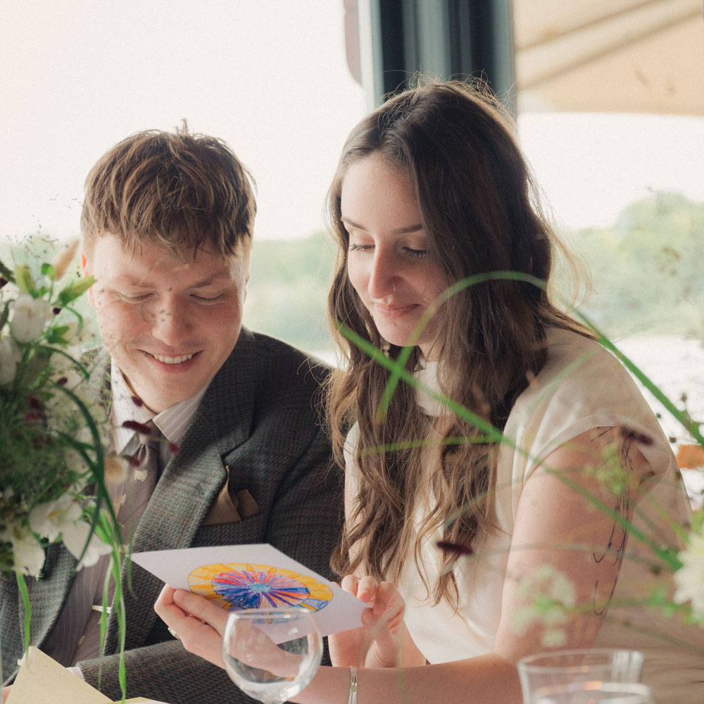 Ein junger Mann schaut sich mit seiner Verlobten eine Einladungskarte an