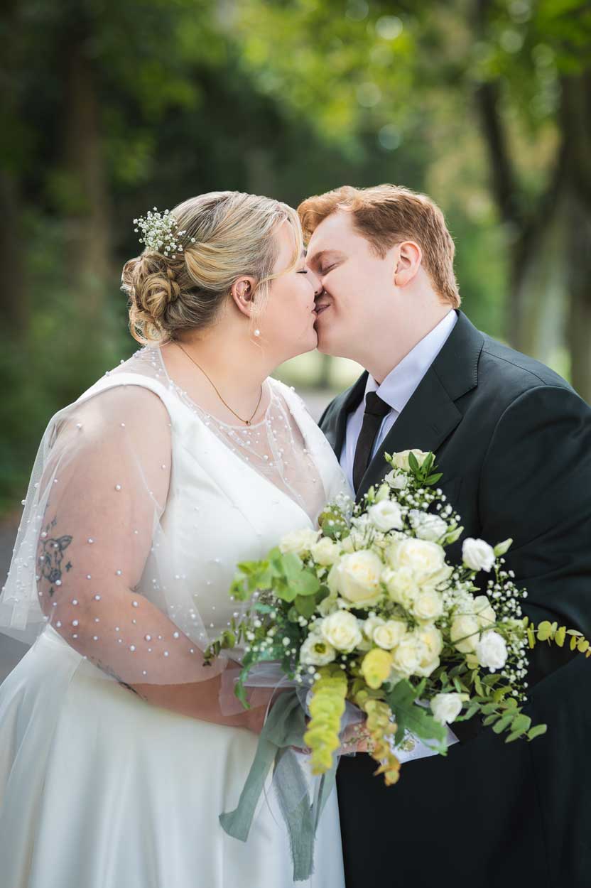 Braut und Bräutigam küssen sich hinter einem Braut und Bräutigam küssen sich hinter dem Brautstrauß