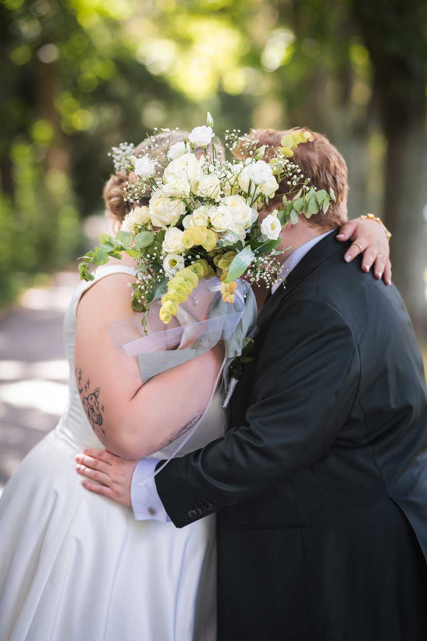 Braut und Bräutigam küssen sich hinter dem Brautstrauß