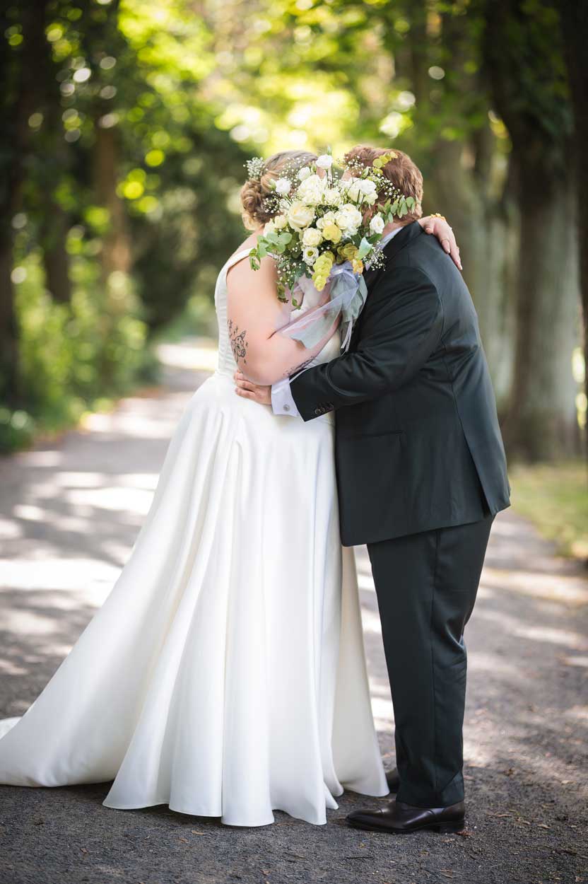 Braut und Bräutigam küssen sich hinter dem Brautstrauß