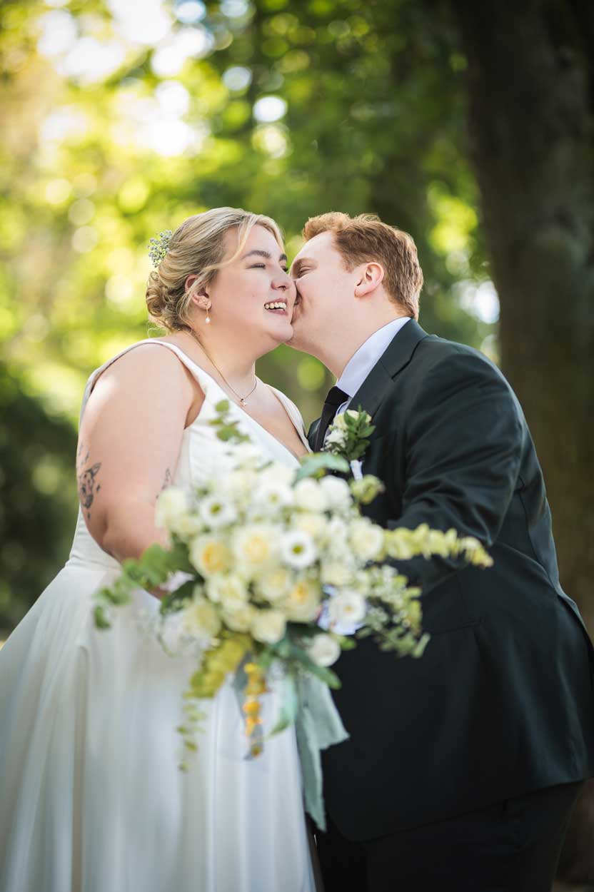 Der Bräutigam küsst die Braut auf die Wange