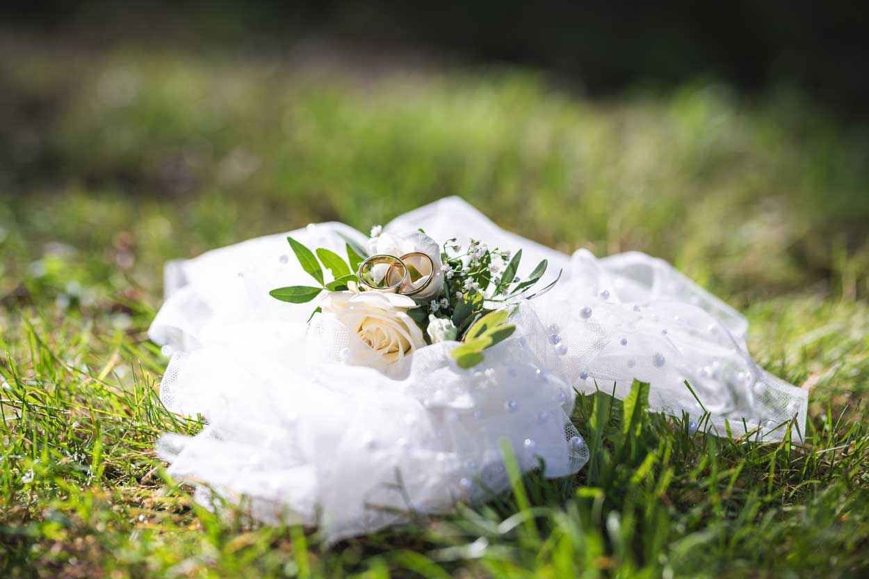 Ein Close-Up Foto der Eheringe auf einem weißen Tuch auf der Wiese