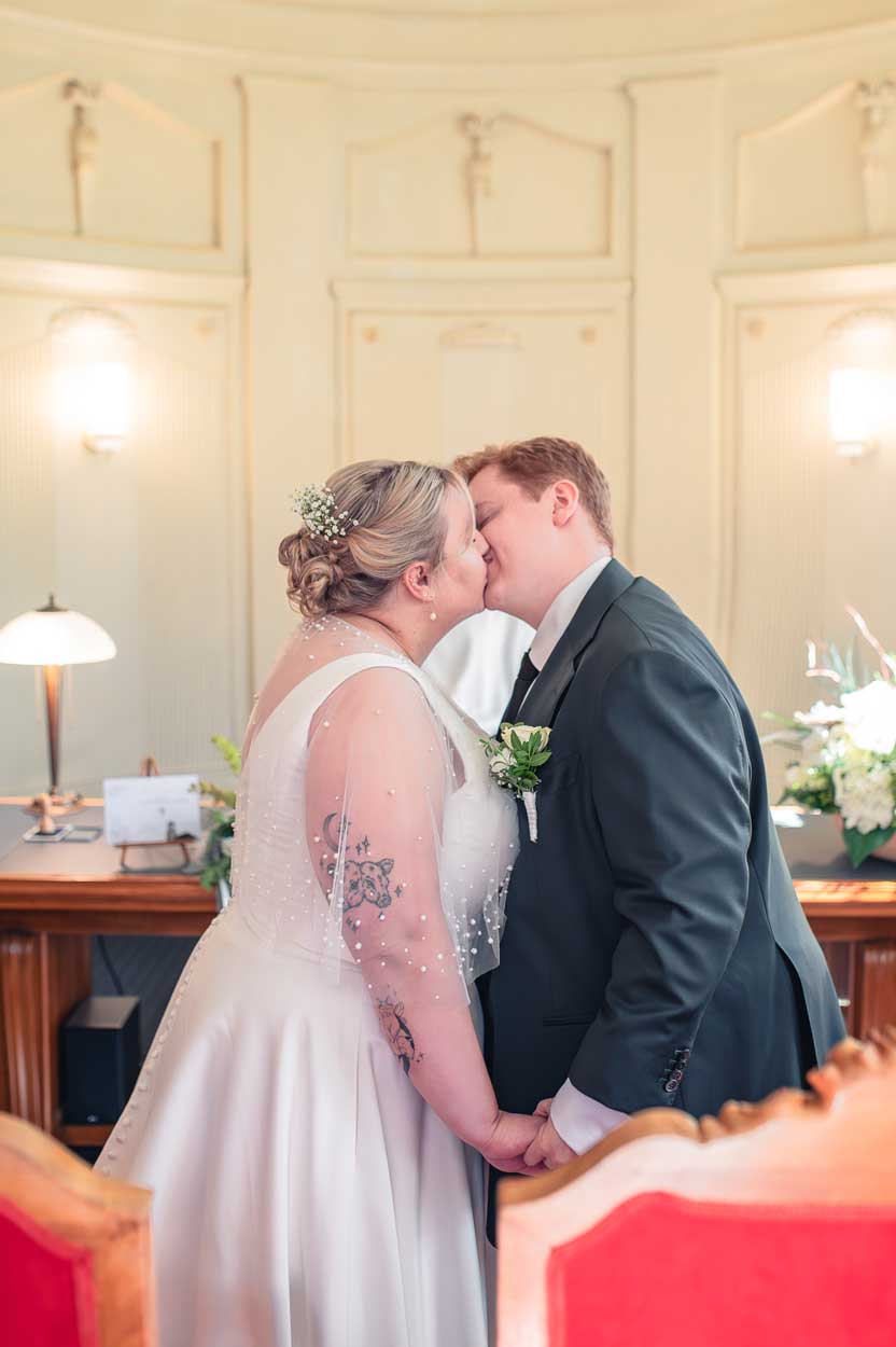 Braut und Bräutigam küssen sich vor dem Standesamt