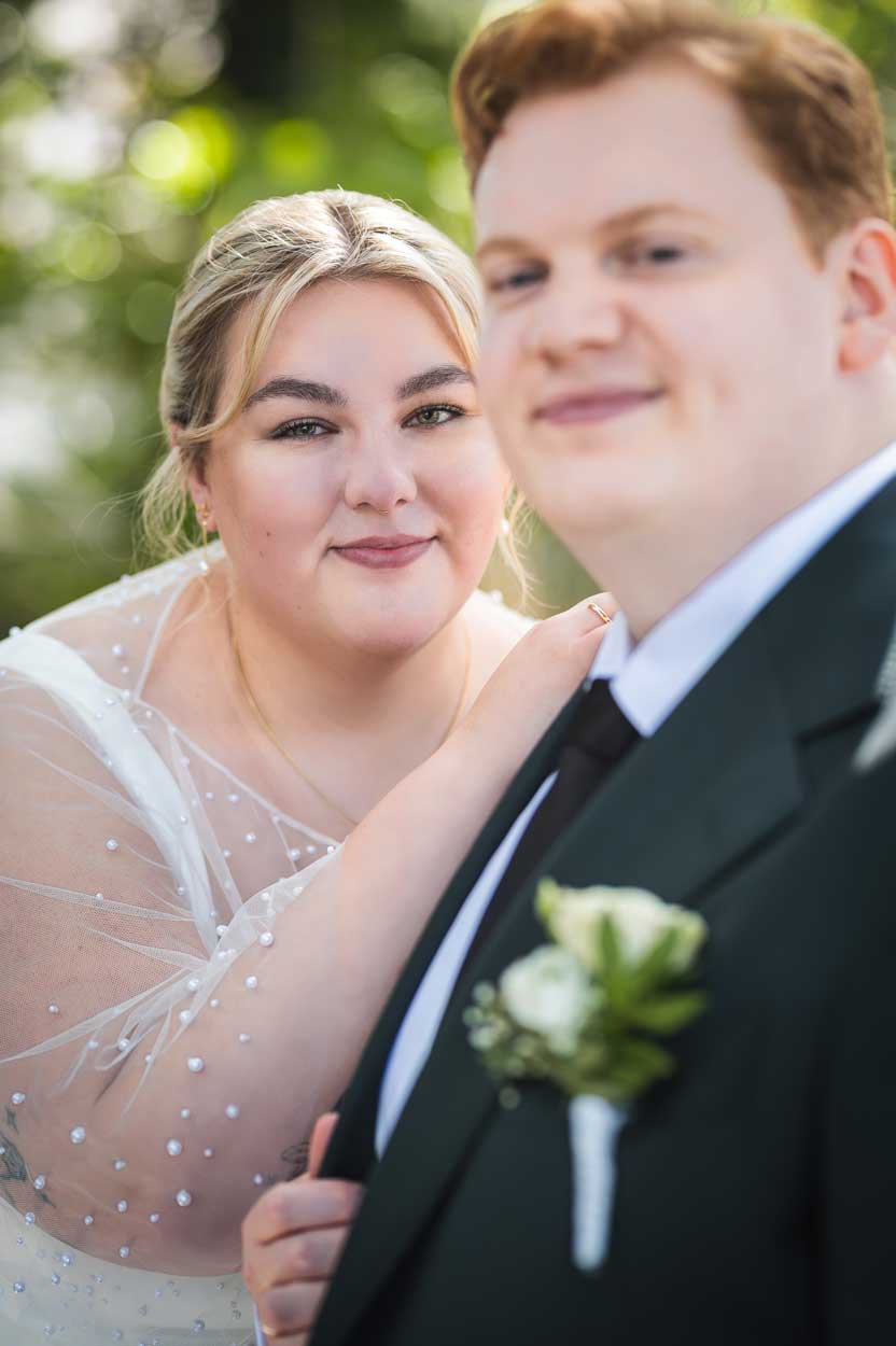 Braut und Bräutigam schauen hintereinander in die Kamera