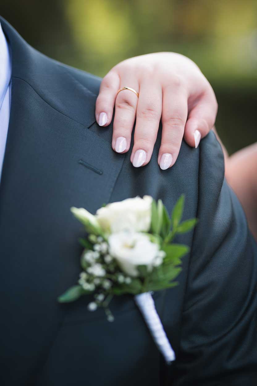 Die Braut legt ihre Hand über die Schulter des Ehemannes