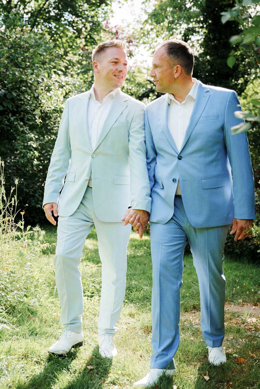 Fotoshooting, zwei Männer laufen Hand in Hand durch den Garten