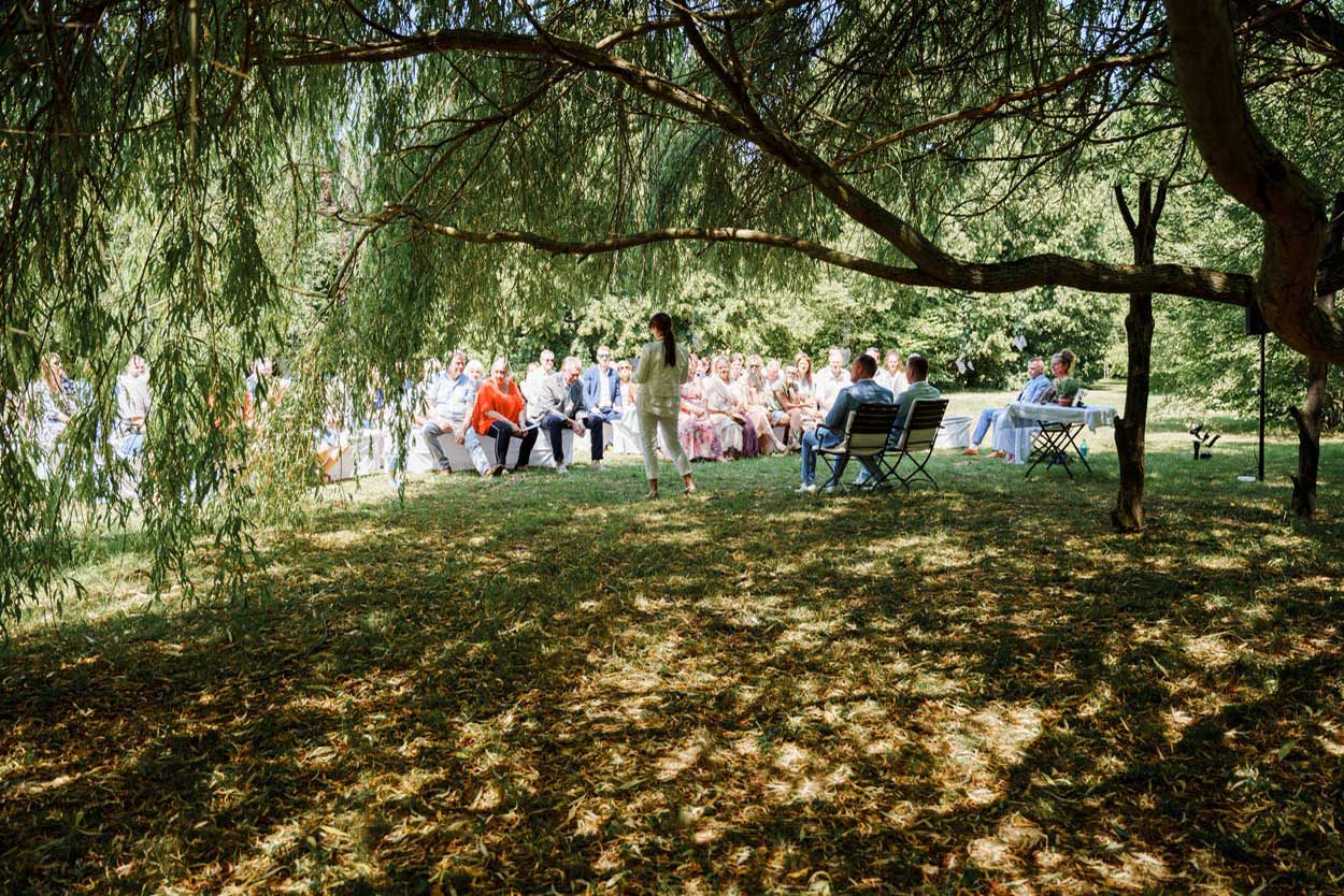 Die Traurednerin steht mit dem Paar unter einem alten Baum