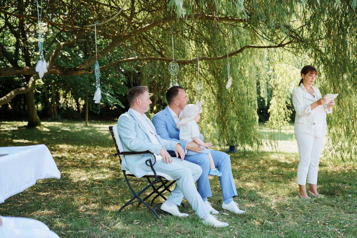 Das Brautpaar sitzt neben der Traurednerin mit einem Kind auf dem Schoß