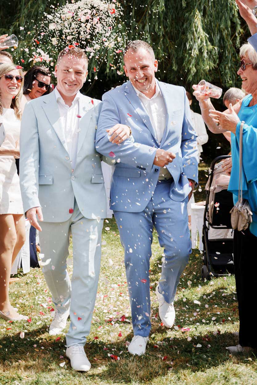 Zwei Männer laufen Hand in Hand durch das Konfetti