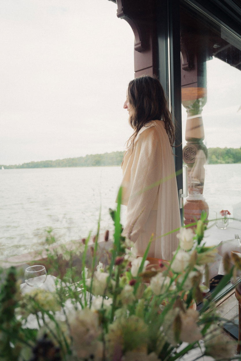 Die Braut steht am Ufer und schaut über den See