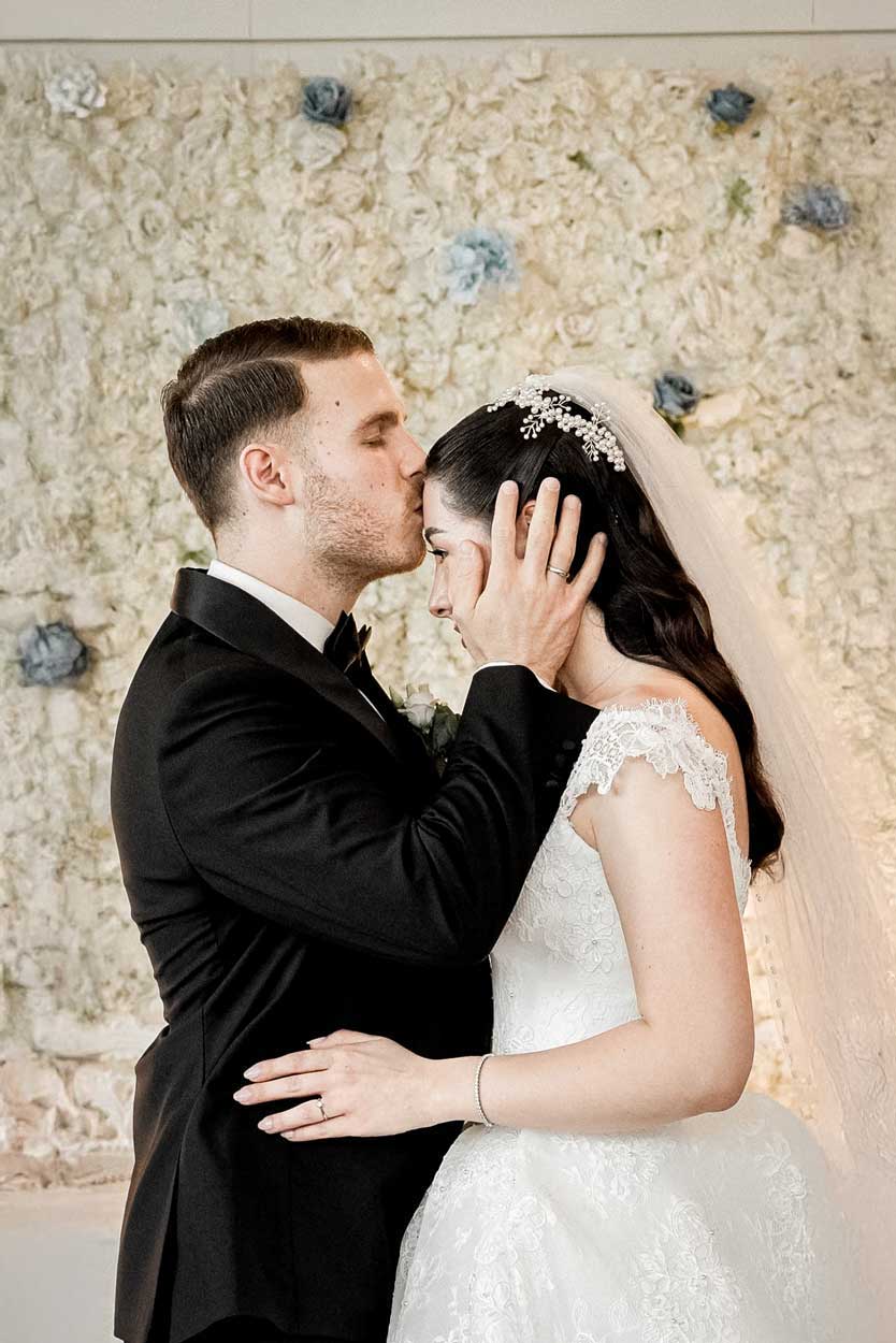 Ein Mann küsst seine Braut auf die Stirn beim Eröffnungstanz