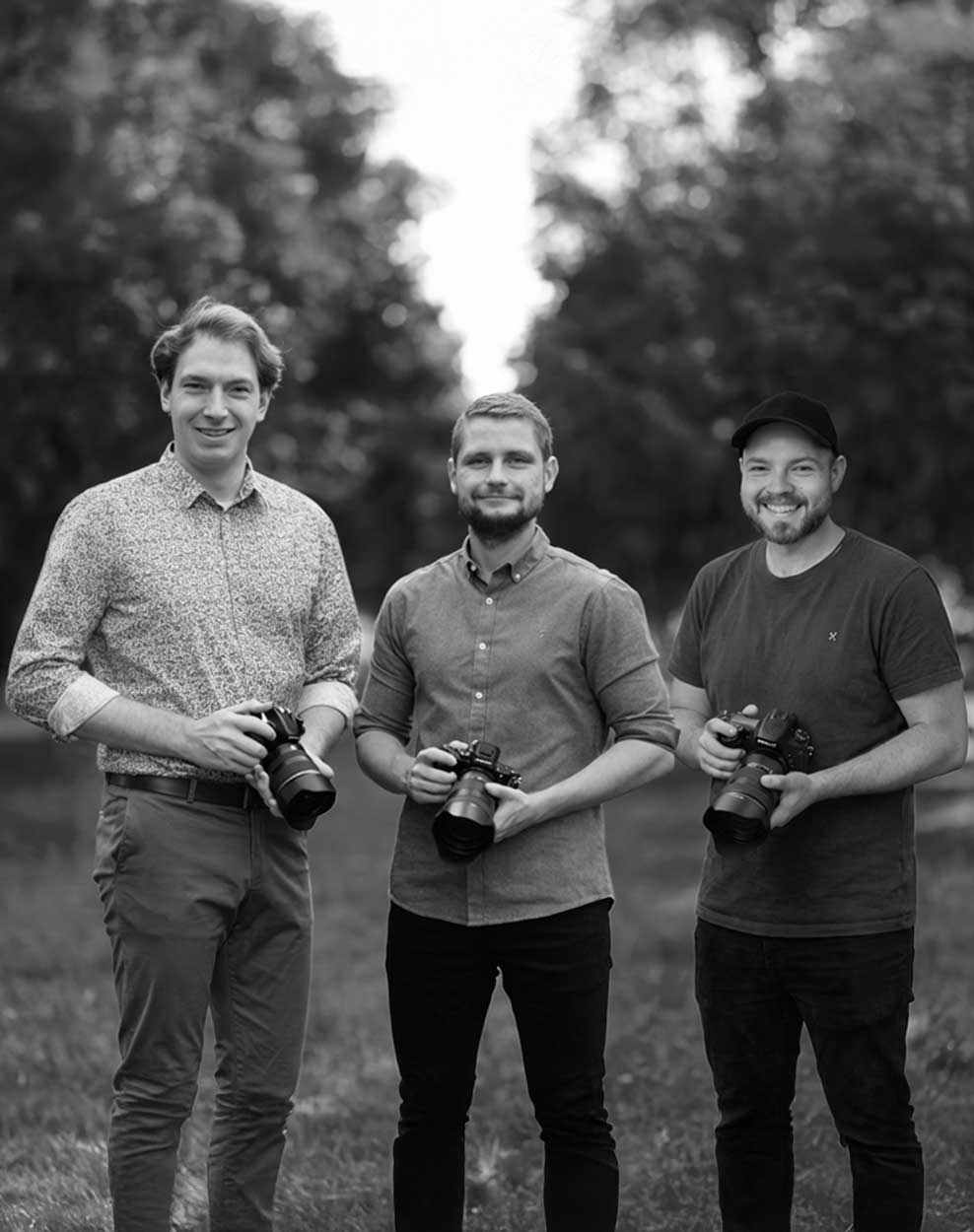 Drei Männer stehen nebeneinander mit ihren Kameras in der Hand