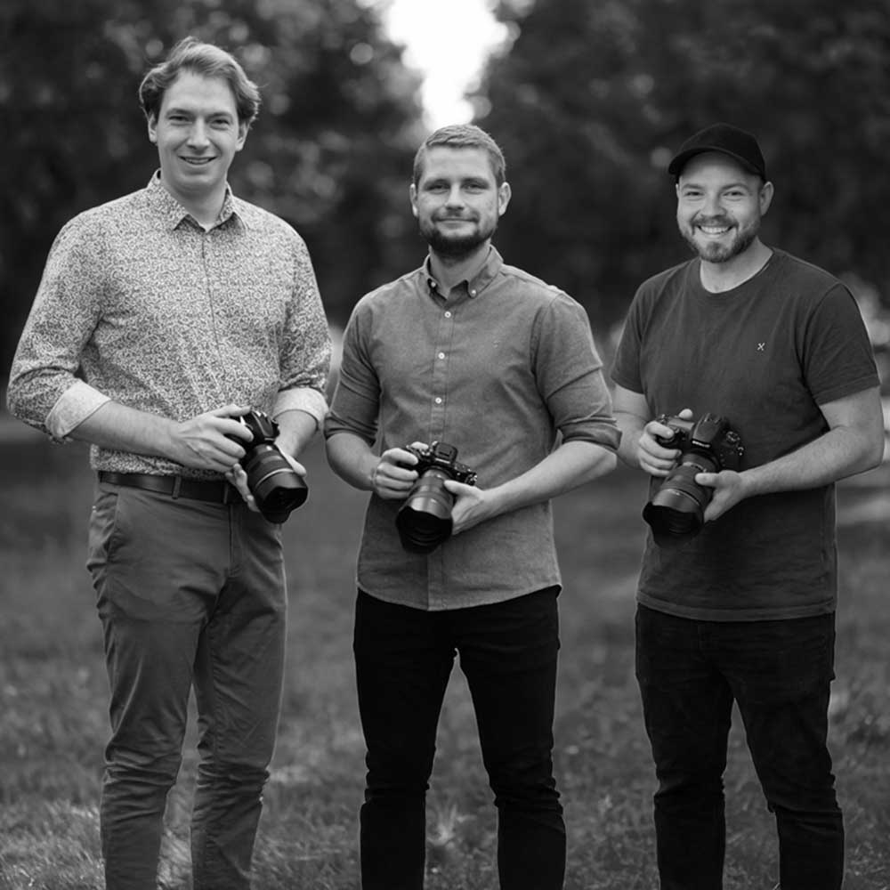 Drei Männer stehen nebeneinander mit ihren Kameras in der Hand